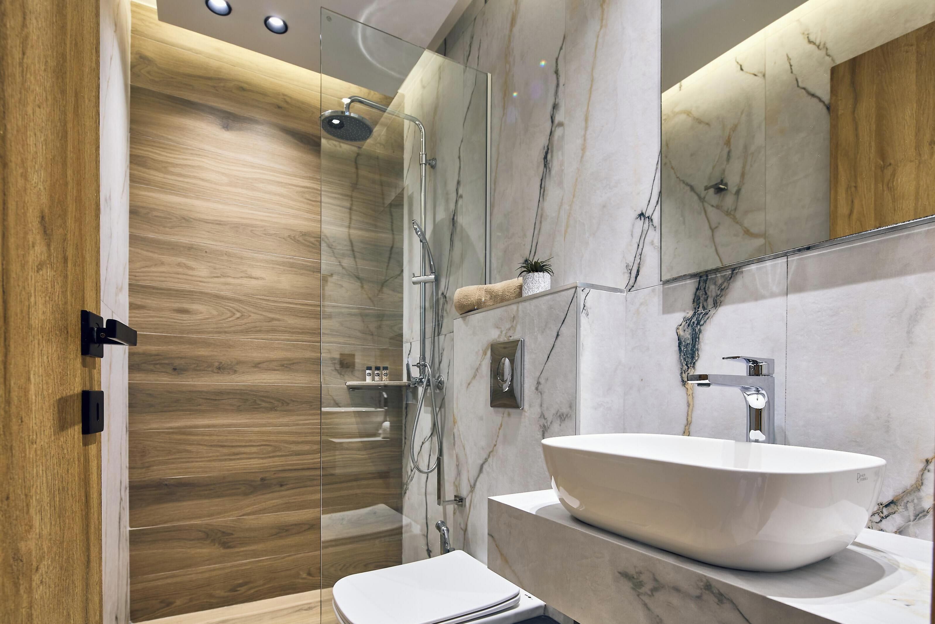 Ein modernes Badezimmer mit einer Duschkabine, einem weißen Waschbecken mit Marmorplatte und Holzelementen.