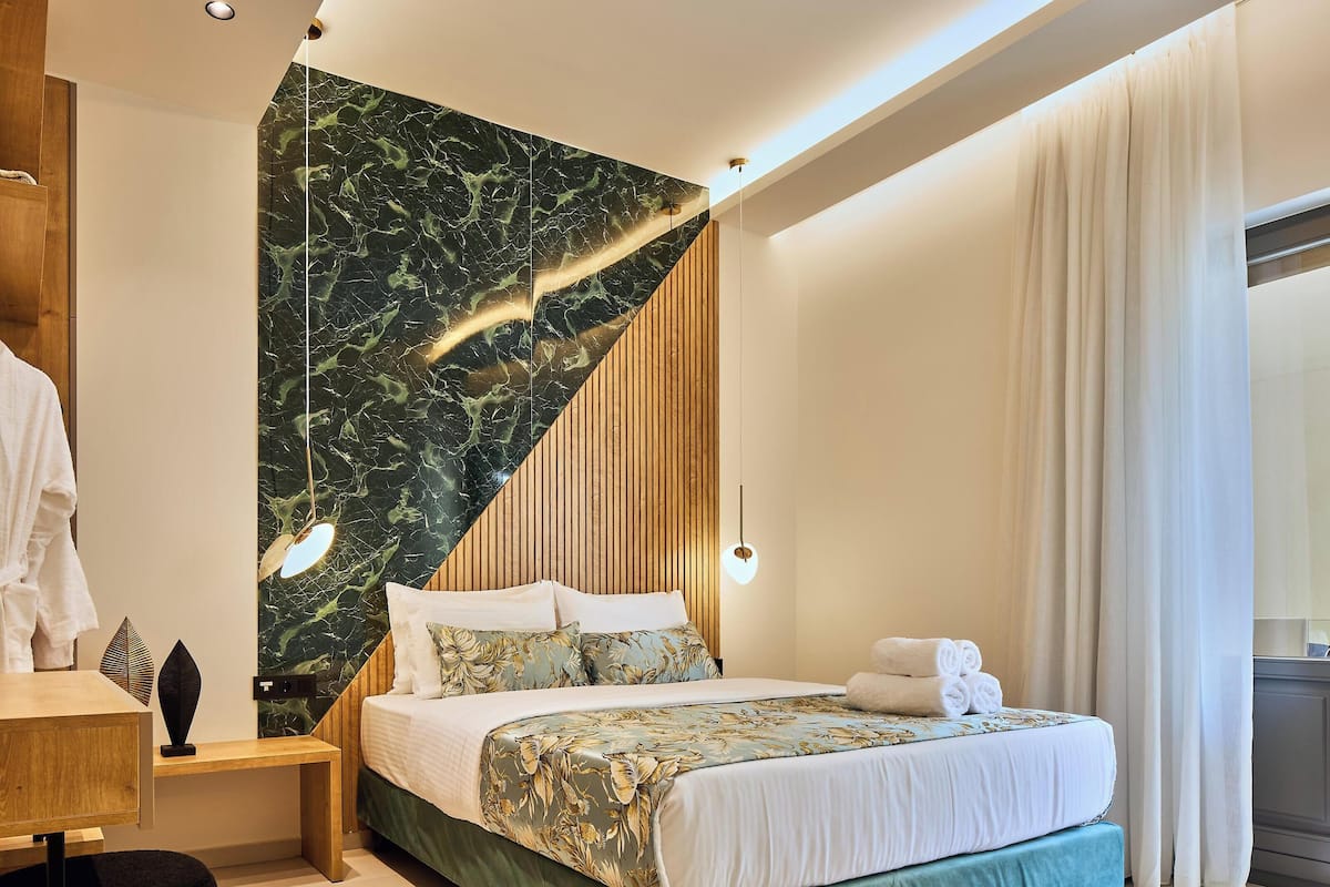 Une chambre d’hôtel moderne avec un lit, un mur lambrissé en bois et un mur d’accent en marbre.