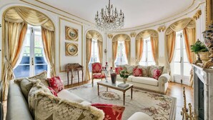A luxurious living room with a chandelier, ornate curtains, and classic furniture. - Parisian Villa: City Views, 5 Bedrooms & Family-Friendly (Paris)