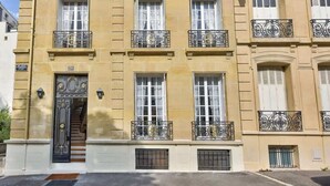 A multi-story building with a symmetrical facade, large windows, and decorative iron railings on the balconies. - Parisian Villa: City Views, 5 Bedrooms & Family-Friendly (Paris)