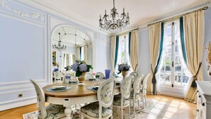 A dining room with a round table, chairs, a chandelier, and a large mirror. - Parisian Villa: City Views, 5 Bedrooms & Family-Friendly (Paris)