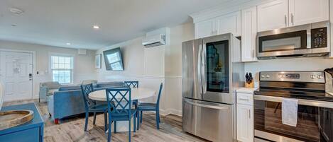 A modern kitchen with white cabinets, stainless steel appliances, and a blue dining area.