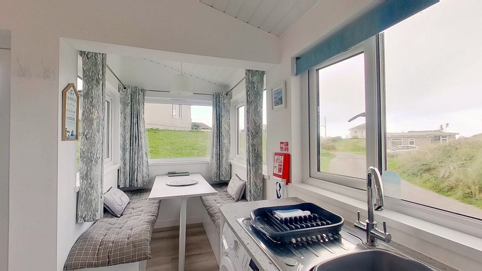A compact kitchenette with a sink, a table, and a bench.