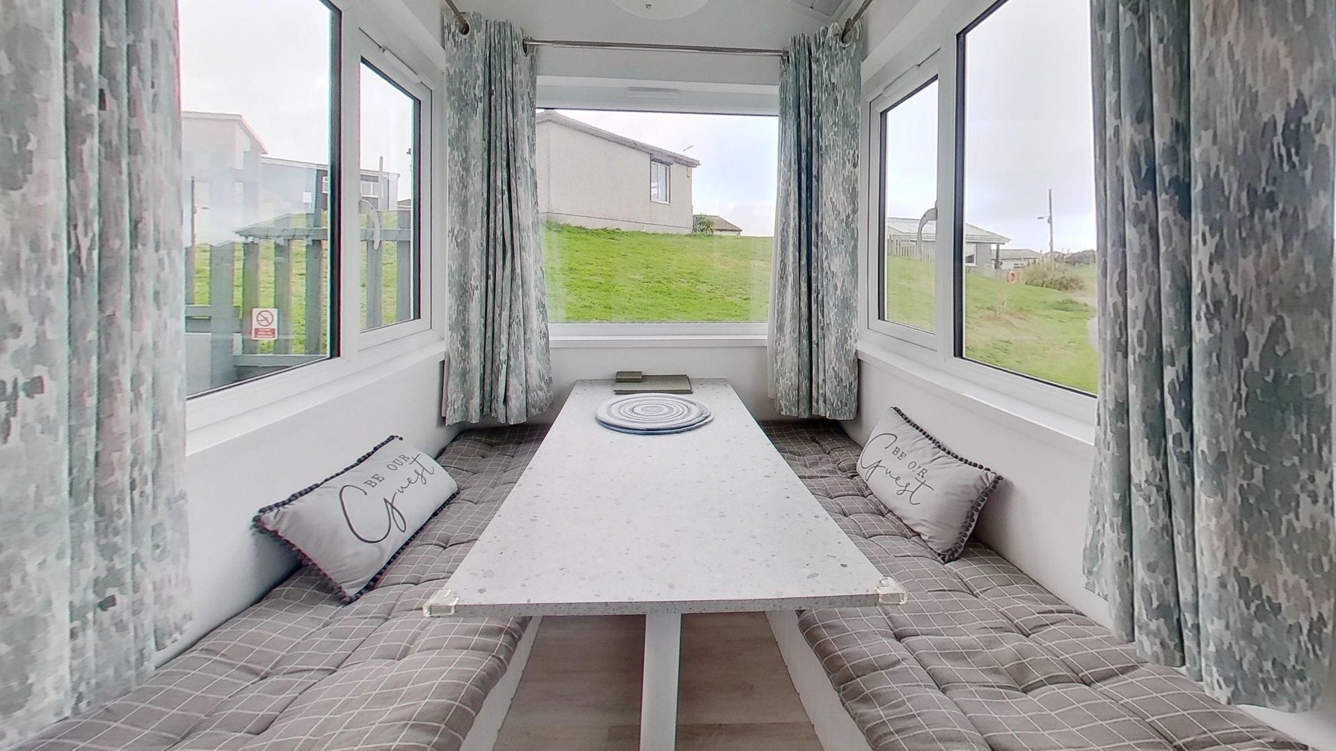 Une pièce dotée d’une longue table, de sièges confortables et de grandes fenêtres.