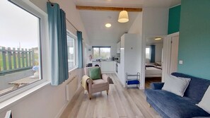 A compact living space with a kitchenette, a sofa, a chair, and a bed. - D37 Irene, Riviere Towans (Hayle)