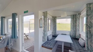 A cozy interior with a bench seating area, a table, and a view of the outside. - D37 Irene, Riviere Towans (Hayle)