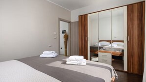 A modern bedroom with a large bed, a wardrobe with mirrored doors, and neatly folded towels on the bed. - Villa dido Nini (Žminj)