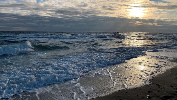 Una spiaggia con onde e un tramonto.