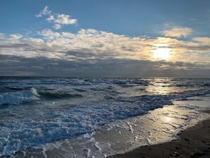 Una playa con olas y un atardecer.