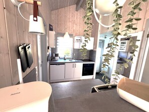 A compact kitchen with modern appliances, a dining area with a bench, and a hanging plant.