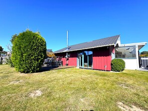 A red building with a covered outdoor area, a chimney, and a well-maintained lawn.