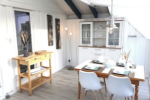 Een eethoek met een houten tafel, witte stoelen en een kast met glazen deuren.