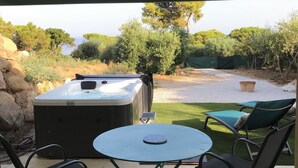 An outdoor patio with a hot tub, two lounge chairs, and a table. - BRAND-NEW SELF-CONTAINED STUDIO WITH GARDEN IN MARINE AREA (Corbara)