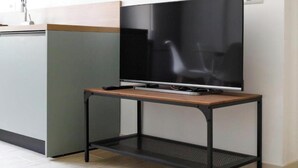 A modern kitchen with a flat-screen TV on a wooden and metal TV stand.
