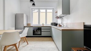 A modern kitchen with a dining area, a built-in oven, a microwave, and a large window.