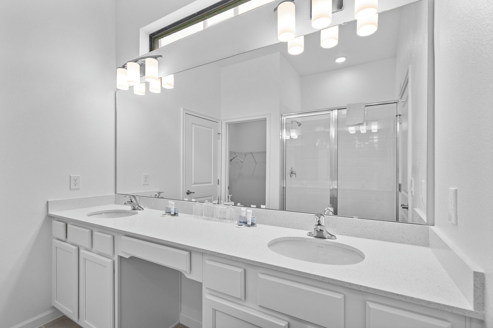 A modern bathroom with two sinks, a large mirror, and a shower.