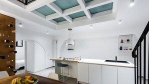A modern kitchen with a central island, white cabinetry, and a hanging pendant light. - The Apple Duplex by Wonderful Italy (Catania)