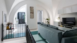 A modern living room with a grey sofa, a TV, and a balcony with a railing. - The Apple Duplex by Wonderful Italy (Catania)