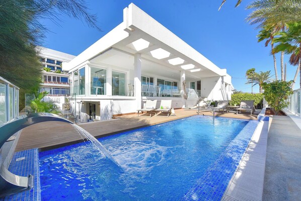 A modern hotel with a swimming pool, outdoor seating, and a covered patio area.