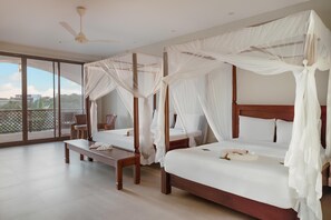 Quarto com duas camas, um ventilador de teto e uma janela grande com vista para o verde.