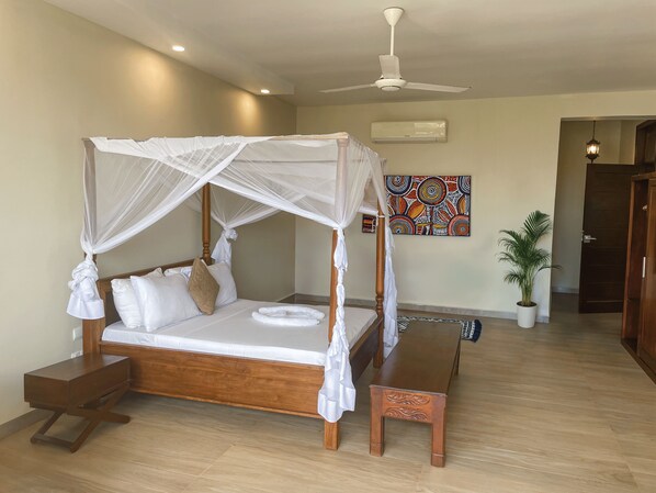 A four-poster bed with a canopy, a wooden bedside table, a bench, and a potted plant.