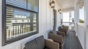 A covered porch with wicker furniture and a view of a residential area. - Beach to Bay 3BR Retreat - Cowboy Pool & Golf Cart (Miramar Beach)