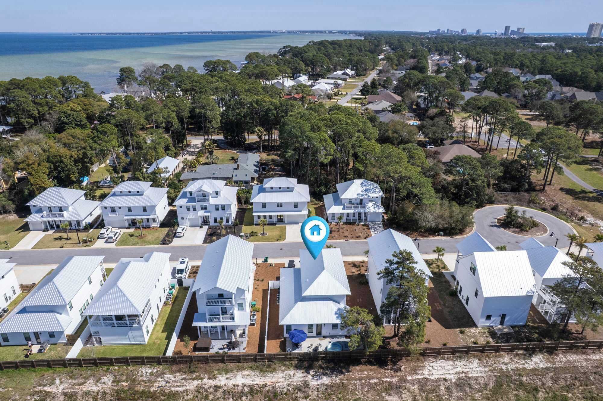 A residential area with modern houses, a clear view of the ocean, and a prominent blue location marker.