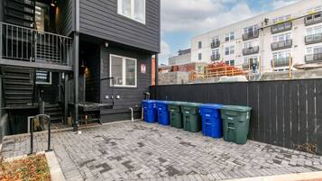 A building with a black exterior, a visible door, and a set of blue and green bins on the ground.