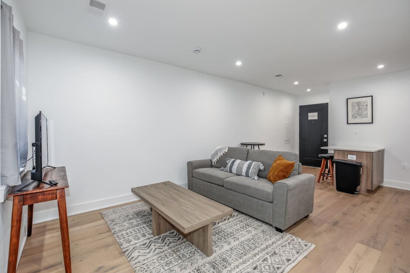 A modern living room with a grey sofa, wooden coffee table, and patterned rugs.