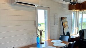 Un comedor con una mesa de madera, sillas negras y vistas al exterior a través de amplios ventanales.
