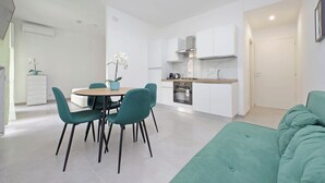 A modern apartment with a dining area, kitchenette, and a green sofa. - YCH Bagnera Suites  (Rome)