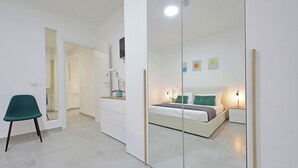 A modern bedroom with a bed, bedside tables, a mirror, and a chair. - YCH Bagnera Suites  (Rome)