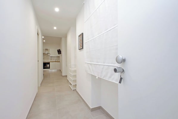 A narrow hallway with white walls and a tiled floor leading to a kitchen area. - YCH Bagnera Suites (Rome)