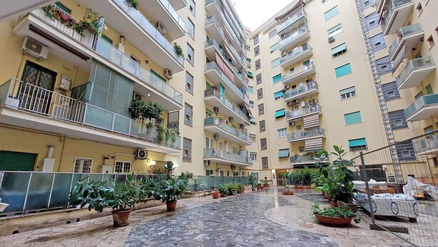 A multi-story residential building with balconies, potted plants, and a tiled courtyard. - YCH Bagnera Suites  (Rome)
