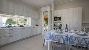 Een moderne keuken met witte kasten, een eethoek met een tafel voor vier personen, en uitzicht op de omgeving door een raam.