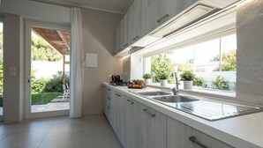 Een moderne keuken met een groot raam, een inbouwspoelbak en een aanrecht met een snijplank.