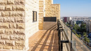 A stone building with a tiled terrace and a view of the city. - Sukoon Hotel Amman (Amman)