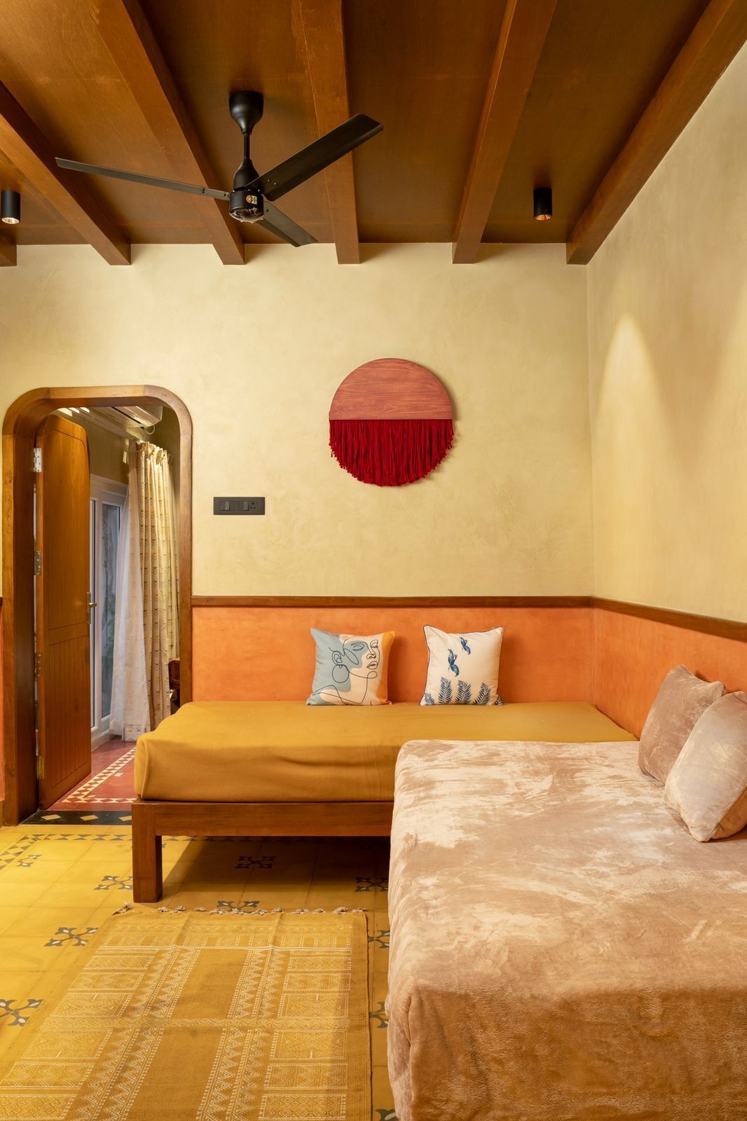 A room with a bed, a ceiling fan, a circular wall decoration, and a patterned rug.