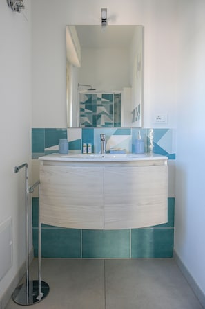 Une salle de bain avec un meuble-lavabo blanc, un miroir et des carreaux de couleur turquoise.