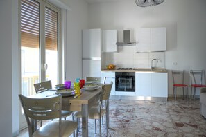 A modern kitchen with white cabinets, a dining table with chairs, and a stove.