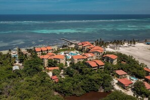 An aerial view of a coastal resort with multiple buildings, a beach, and a pier.