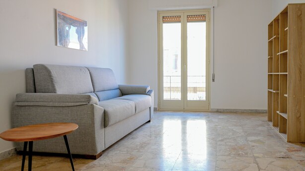 A living room with a sofa, a small wooden table, and a wooden shelving unit.