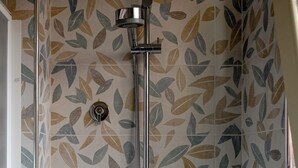 A shower with a leaf-patterned tile wall and a chrome showerhead.