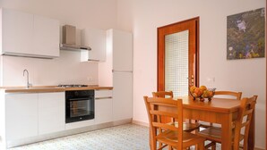 A kitchen with white cabinets, a black oven, and a dining table with chairs.