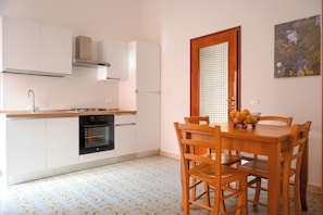 A kitchen with white cabinets, a black oven, and a dining table with chairs.