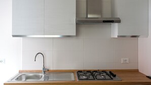 A modern kitchen with a stainless steel sink, gas stove, and white cabinets.
