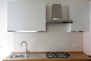 A modern kitchen with a stainless steel sink, gas stove, and white cabinets.