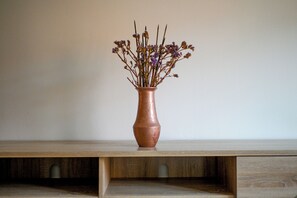 A vase with dried flowers on a wooden shelf.