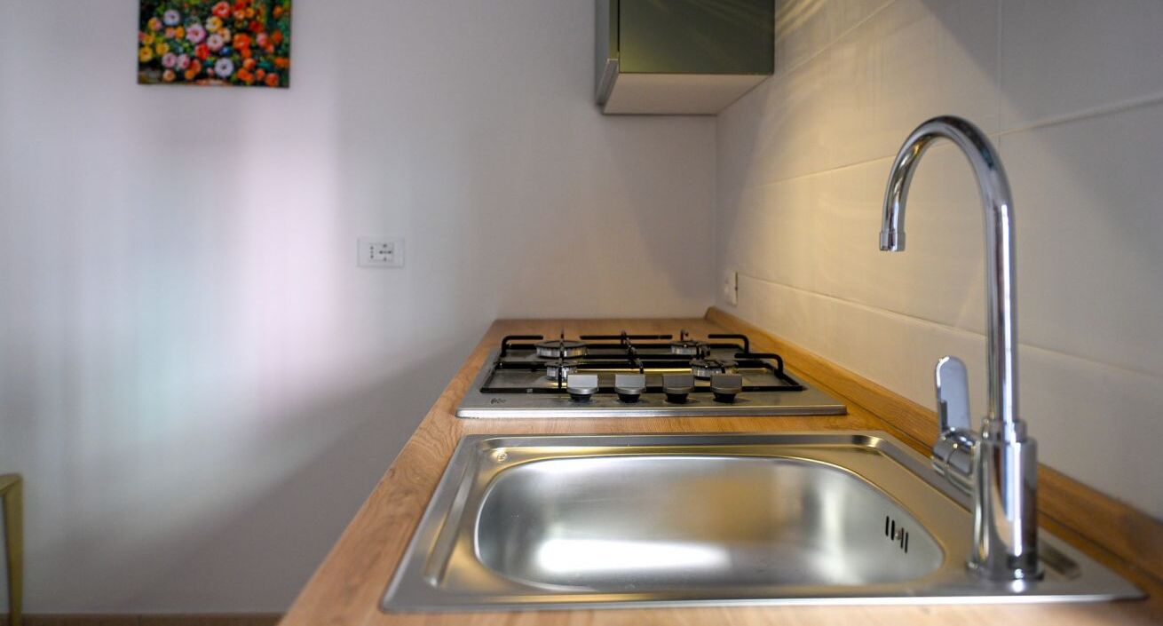 Een koelkast, een oven, een kookplaat, kookgerei, borden en bestek