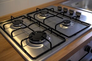 A gas stove with four burners and a control panel.